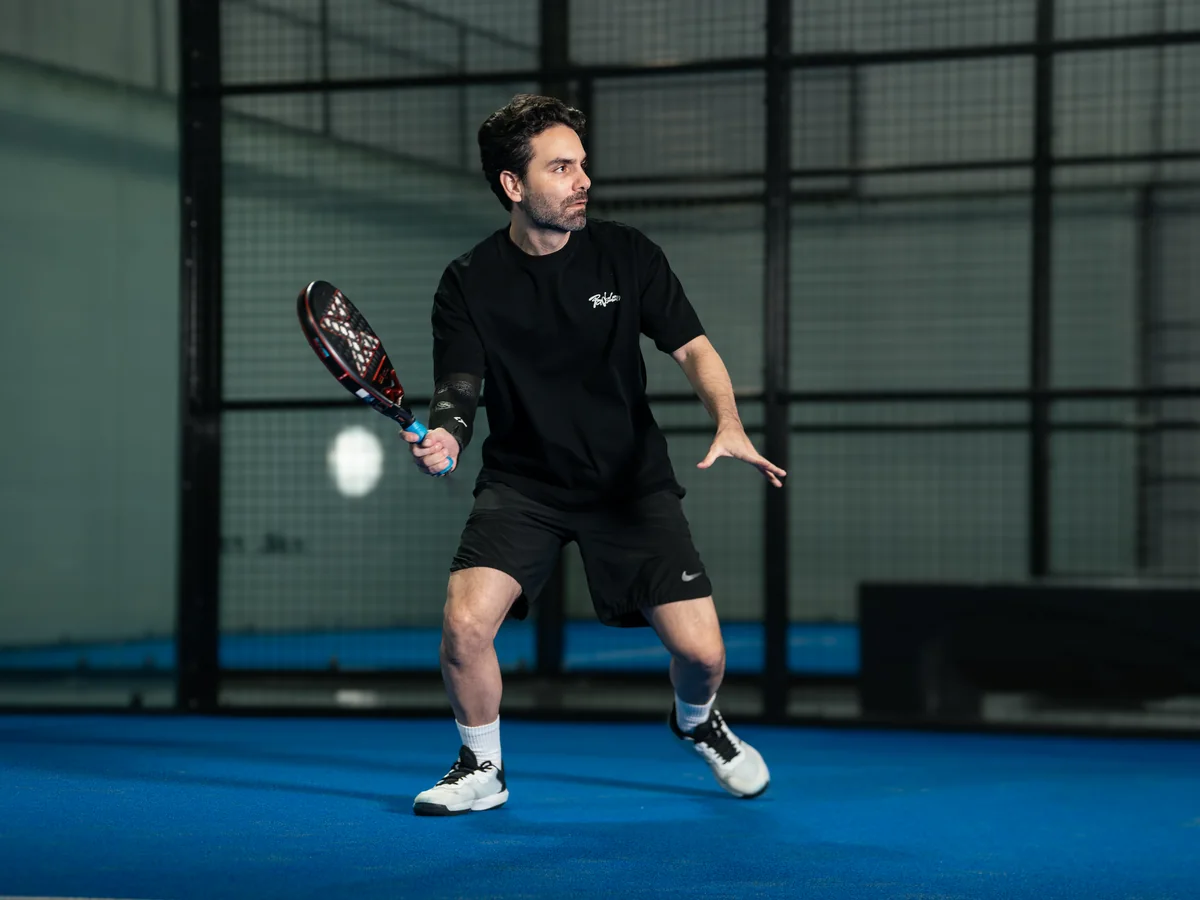 A player waits in position with the racket back, watching the ball.