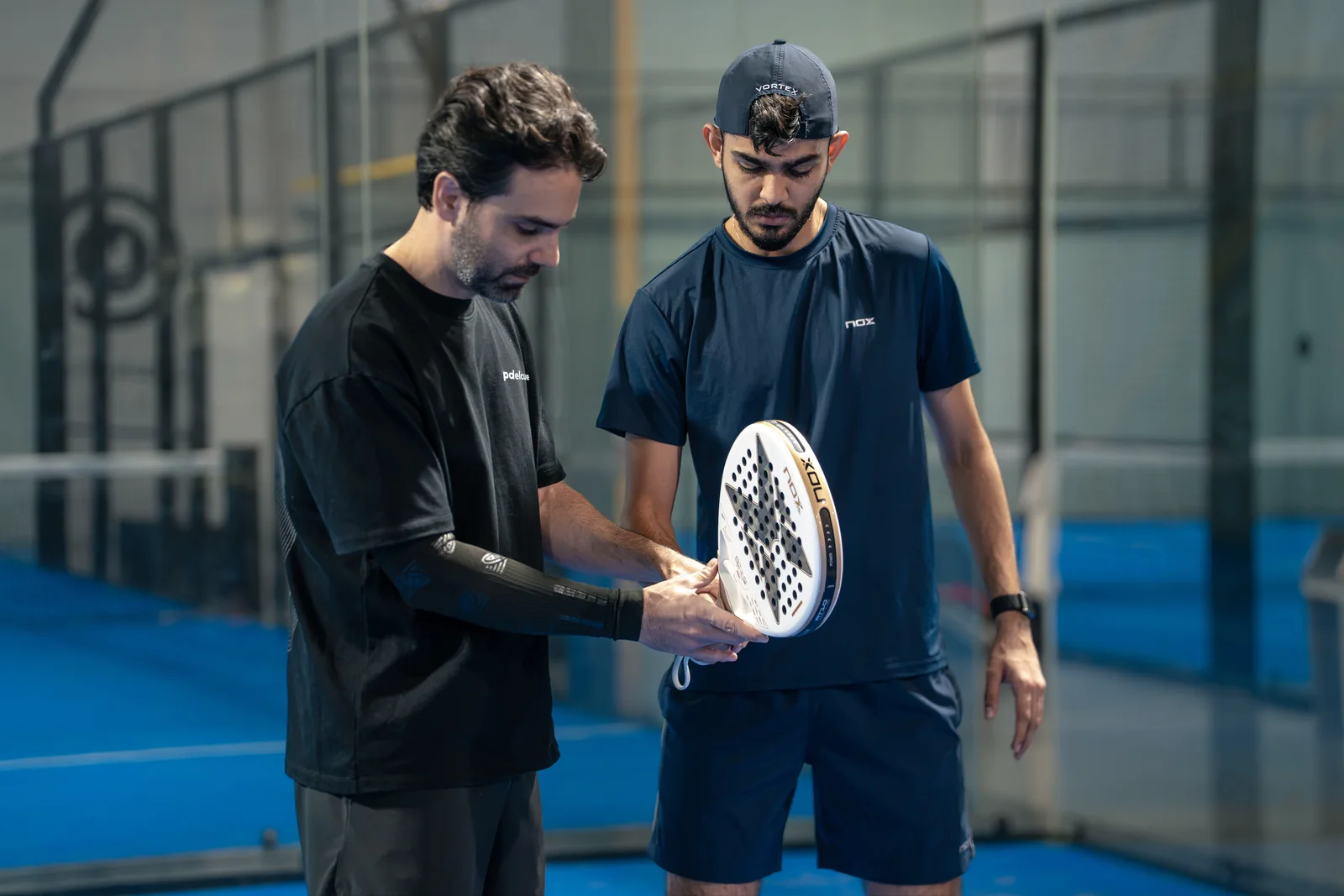 A coach shows a player the grip on the racket, on court.