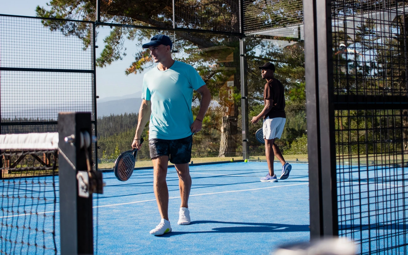 Two men playing padel on an outdoor court.
